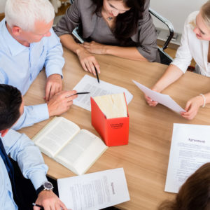 Lawyers in law firm reading documents and agreements at large conference table